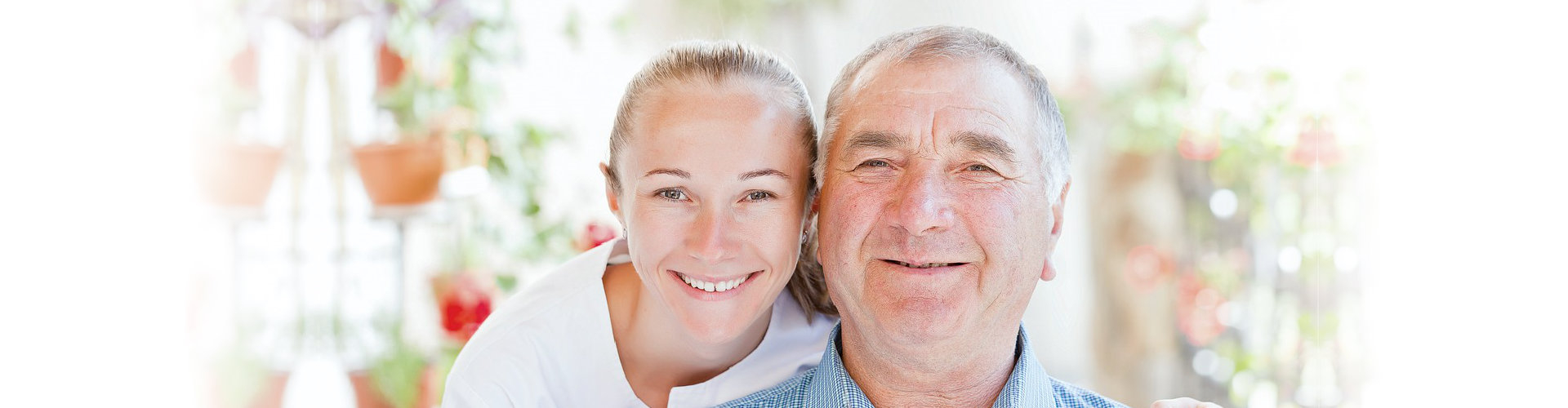 caregiver and an elderly man smiling at the camera