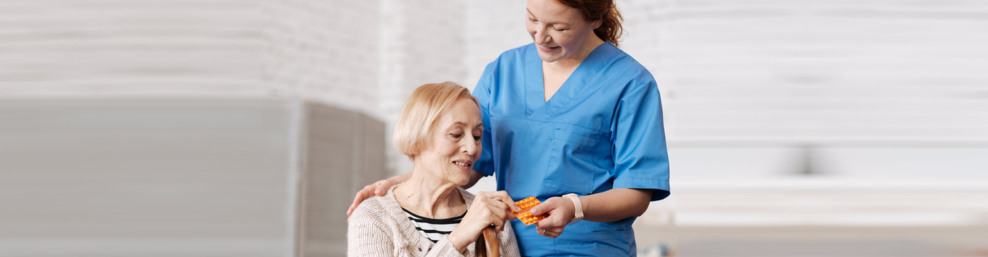 caregiver giving medicine to senior woman
